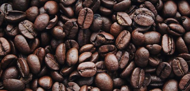 A detailed view of aromatic roasted Arabica coffee beans, highlighting texture and brown color.