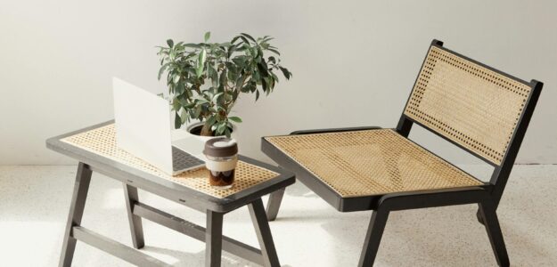 Stylish minimalist interior featuring a rattan chair, table, and laptop with a potted plant.